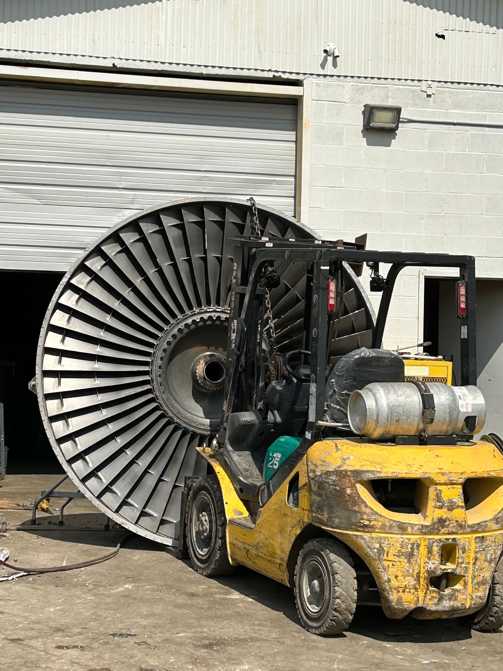 Large jet-engine fan section being moved by forklift